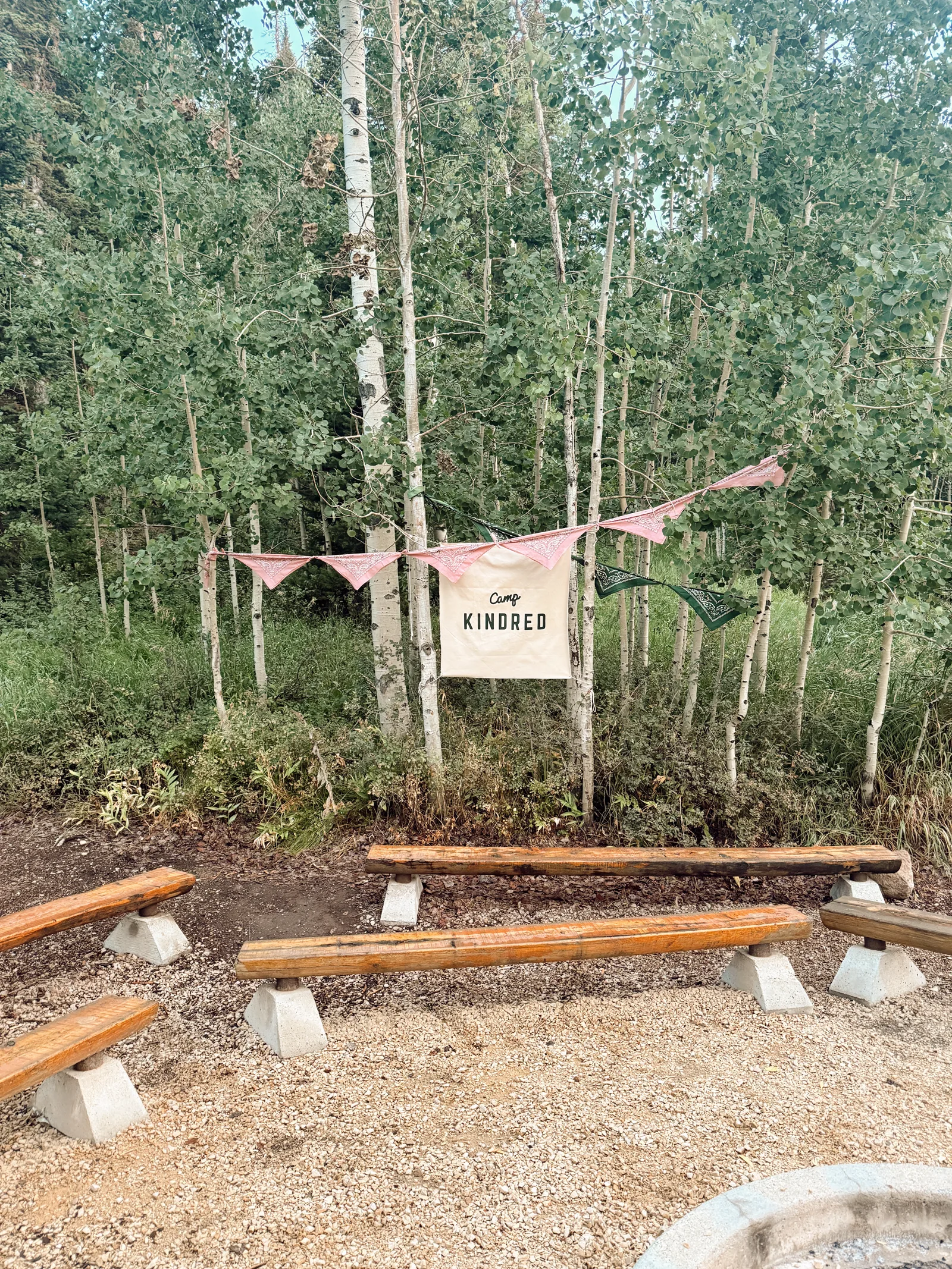 A quiet Camp Kindred gathering space with a banner among the aspen trees